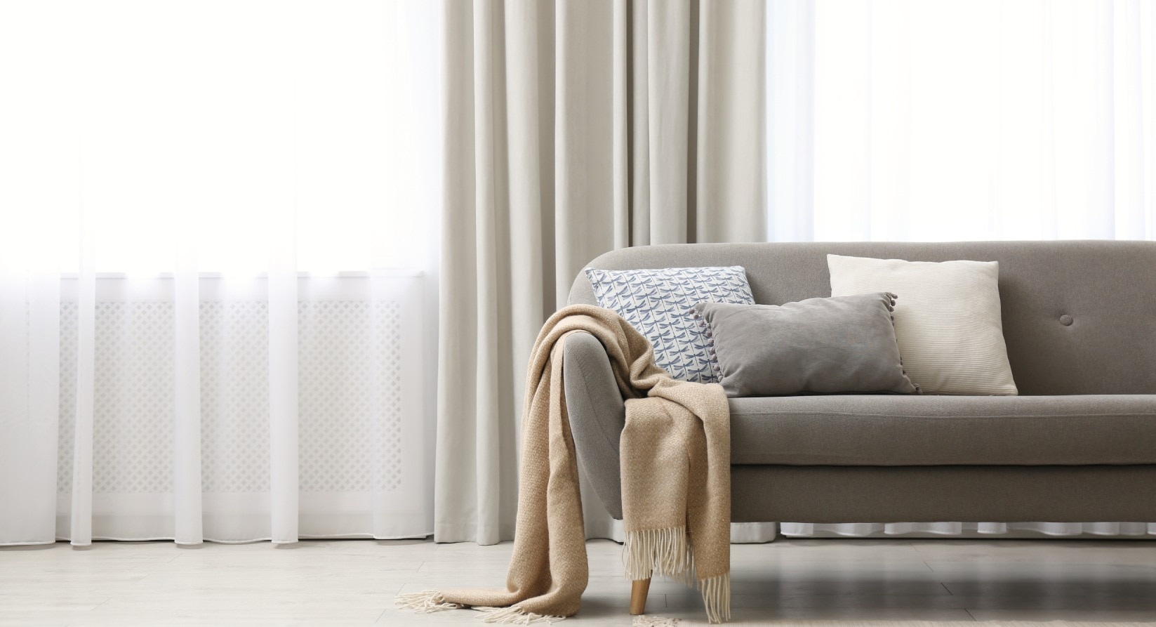 Sala de estar com um sofá cinza e uma cortina bege